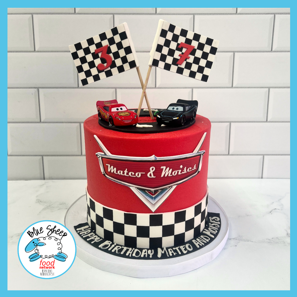 Vibrant red race car themed birthday cake with checkered flag design, toy cars on top, and personalized birthday message for a festive celebration.
