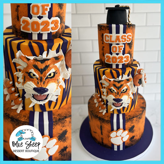A Clemson University-themed graduation cake with tiger motifs, paw prints, and 'CLASS OF 2023' on a bold orange and purple background.