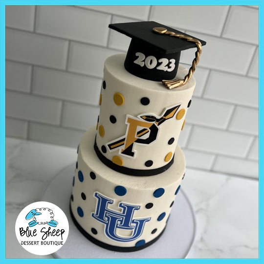 A two-tiered graduation cake in Piscataway High School's colors with logos, polka dots, and a 2023 graduation cap topper.