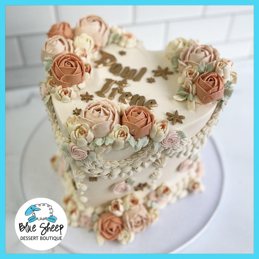 Custom heart-shaped birthday cake with floral decoration and personalized text in a dessert boutique setting.