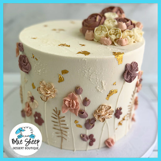 Elegant custom cake with intricate wildflower fondant designs and gold leaf, ideal for birthdays or bridal showers.