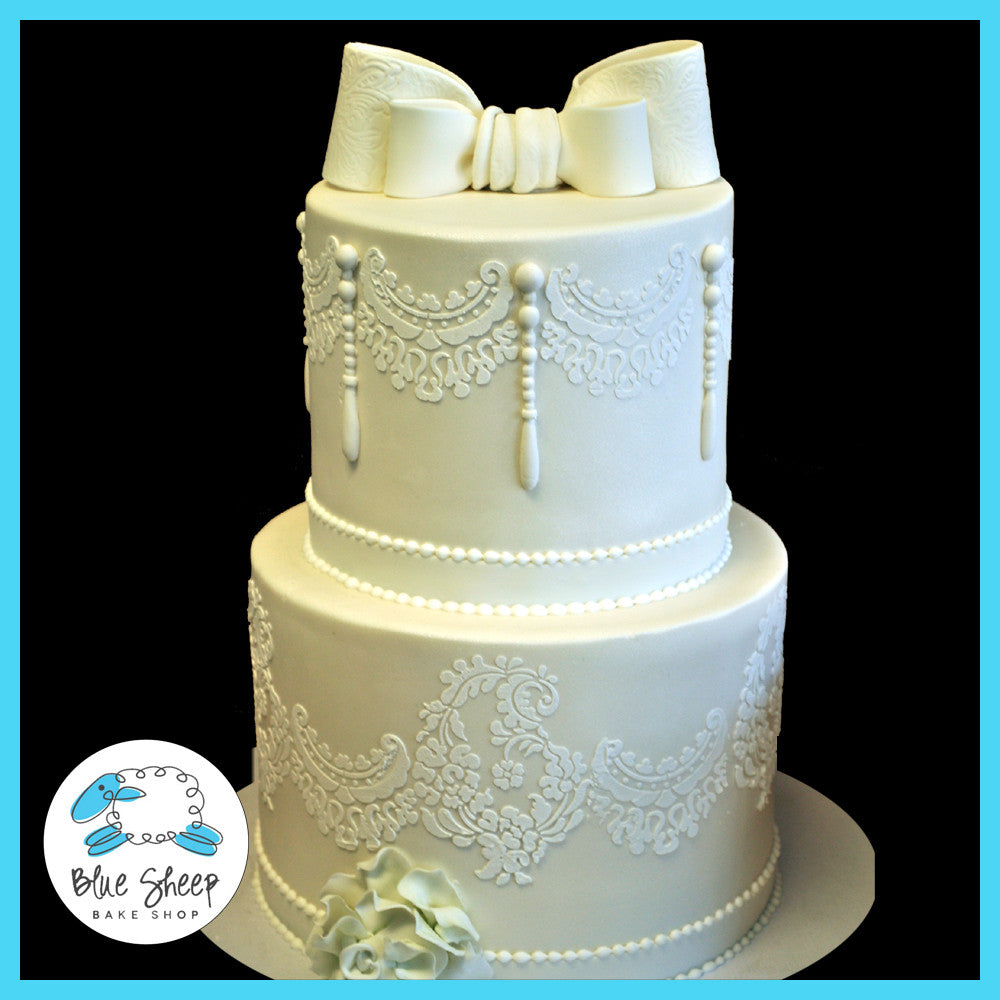 white lace wedding cake with pearls and bow