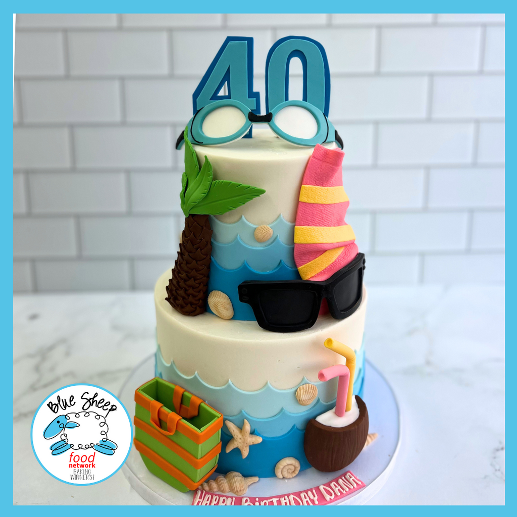 Two-tier beach-themed 40th birthday cake with number 40 topper, fondant sunglasses, towel, and beach accessories on a sandy fondant base.