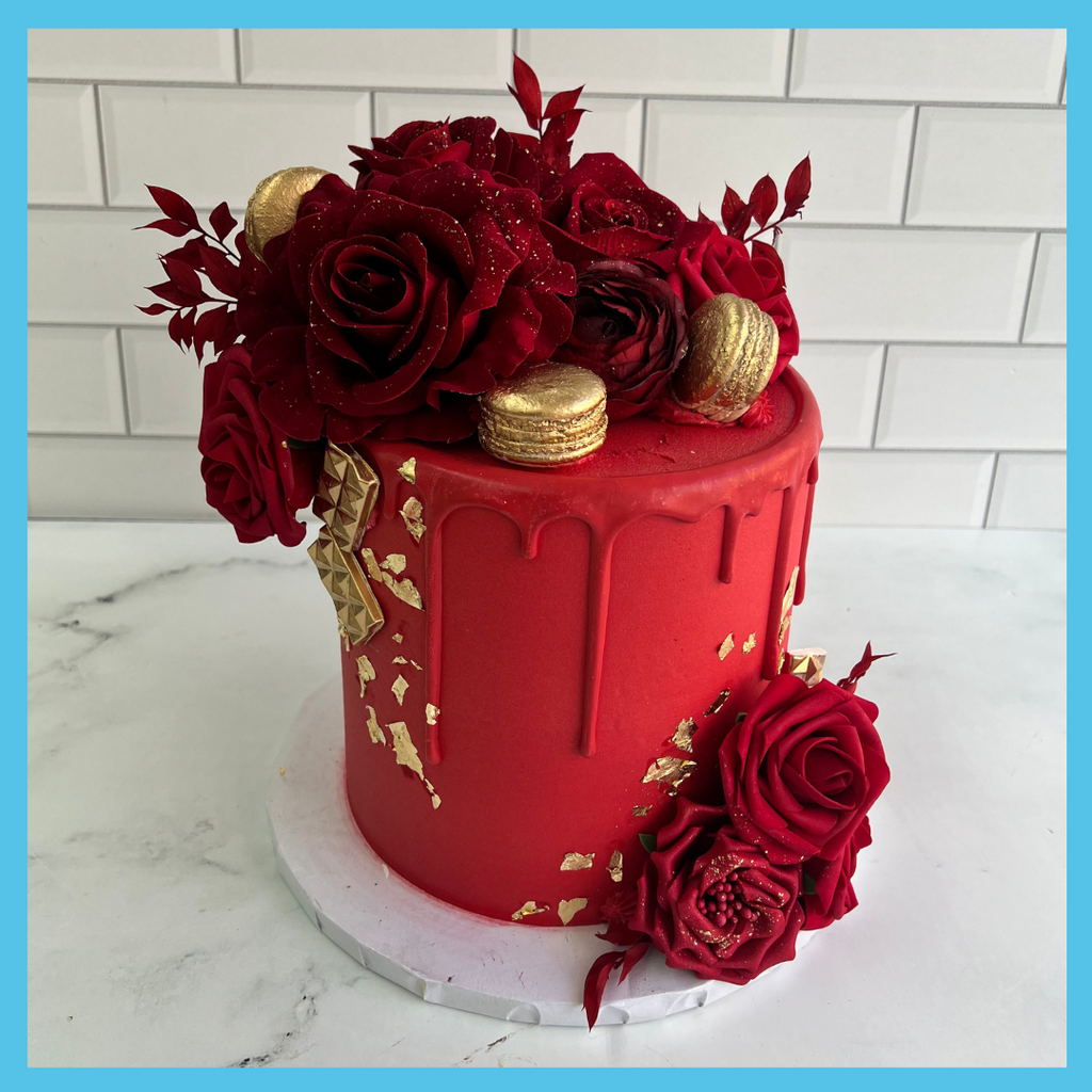 Opulent red and gold cake with a glossy red drip effect, adorned with edible roses and gold leaf accents for a luxurious celebration.