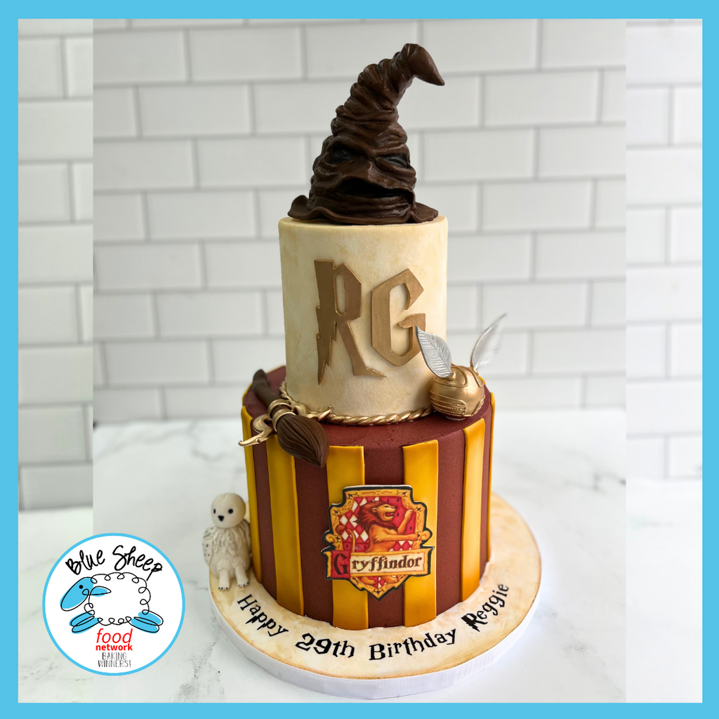 Fantasy wizard-themed birthday cake with house crest, chocolate hat topper, and golden snitch, personalized for a magical celebration.