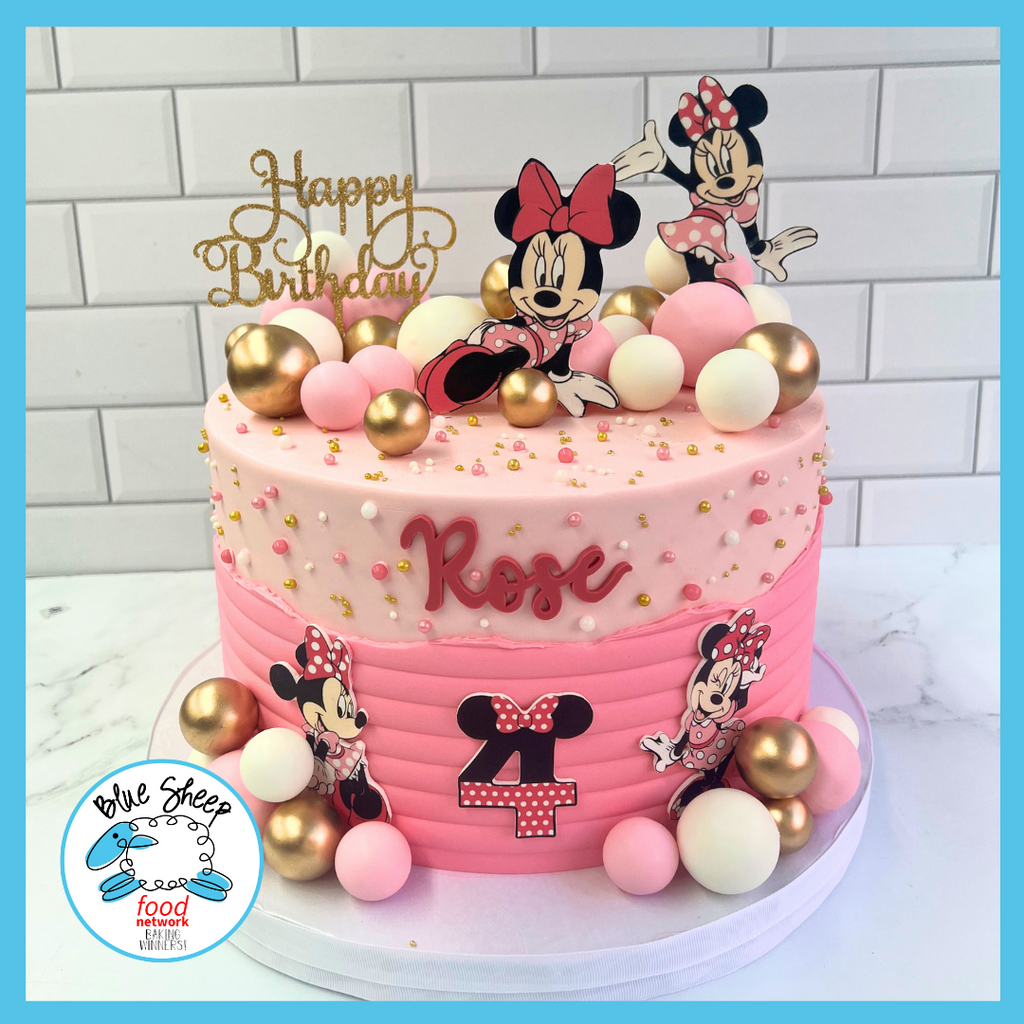 Two-tiered pink birthday cake with beloved cartoon character decorations, golden orbs, and a custom name, ideal for a children's party.