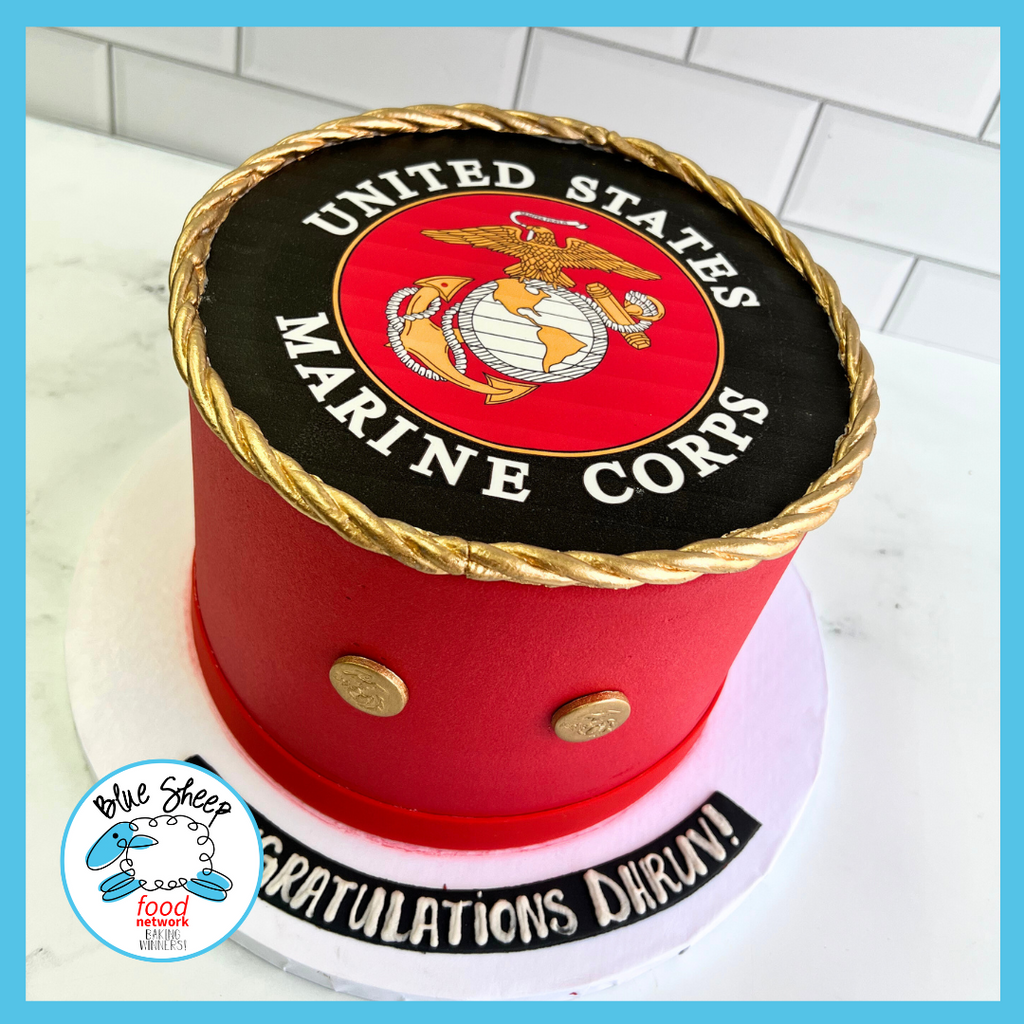 Custom red and white celebration cake with Marine Corps emblem and gold rope detailing for military graduation.