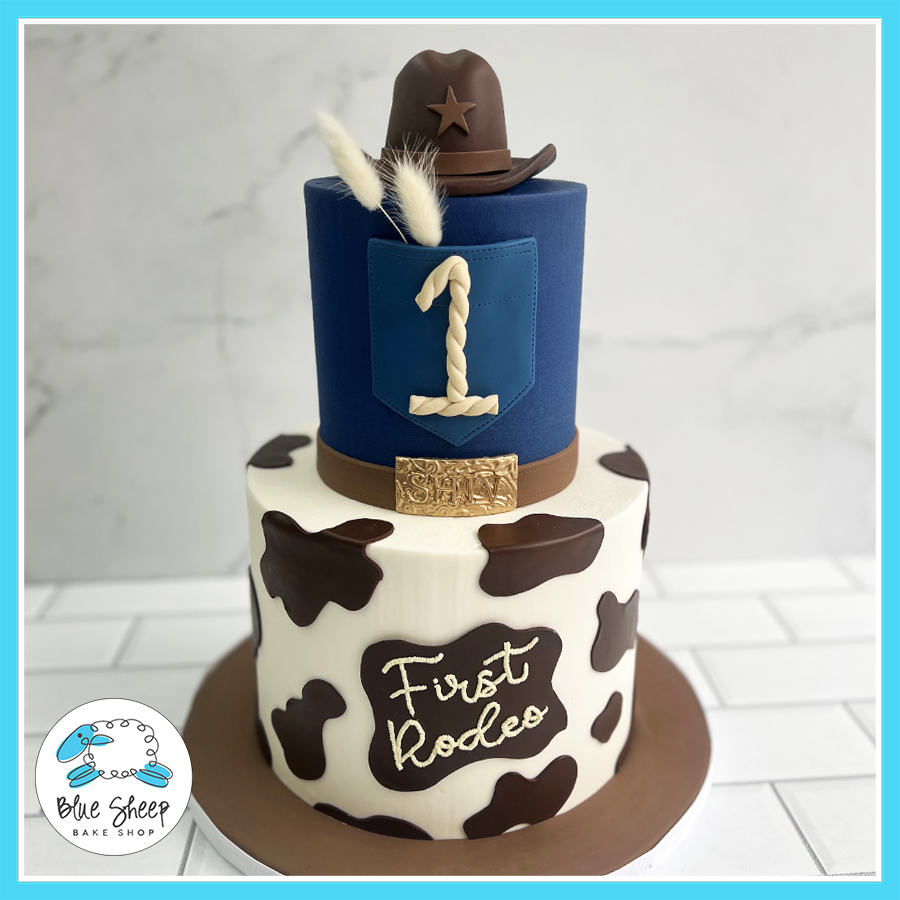 Cowboy rodeo 1st birthday cake with cow print and cowboy hat 
