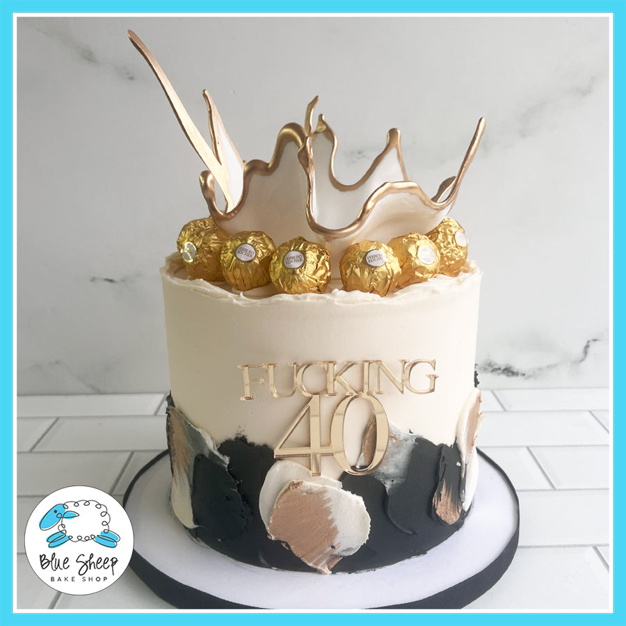 Bold "F***ing 40" birthday cake with black and gold brushstrokes, Ferrero Rocher chocolates, and a golden chocolate crown by Blue Sheep Bake Shop in Somerville, NJ.

