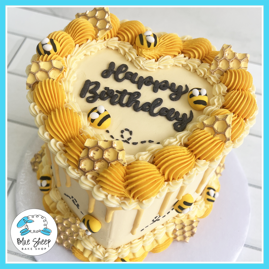 Bee-themed heart-shaped birthday cake with yellow buttercream swirls, honeycomb details, and fondant bees – Blue Sheep Bake Shop Somerville NJ