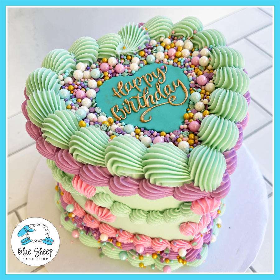 Pastel heart-shaped birthday cake with vintage-inspired buttercream piping, pearl sprinkles, and a “Happy Birthday” topper, available at Blue Sheep Bake Shop in Somerville, NJ