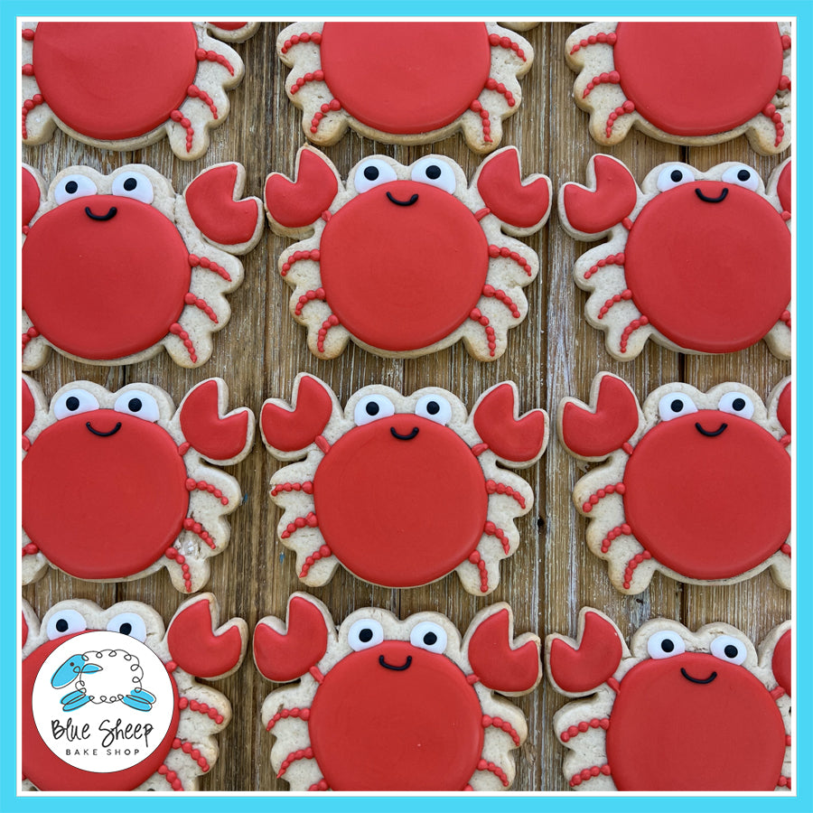 Adorable crab-shaped cookies with red icing and playful expressions, perfect for beach-themed parties.