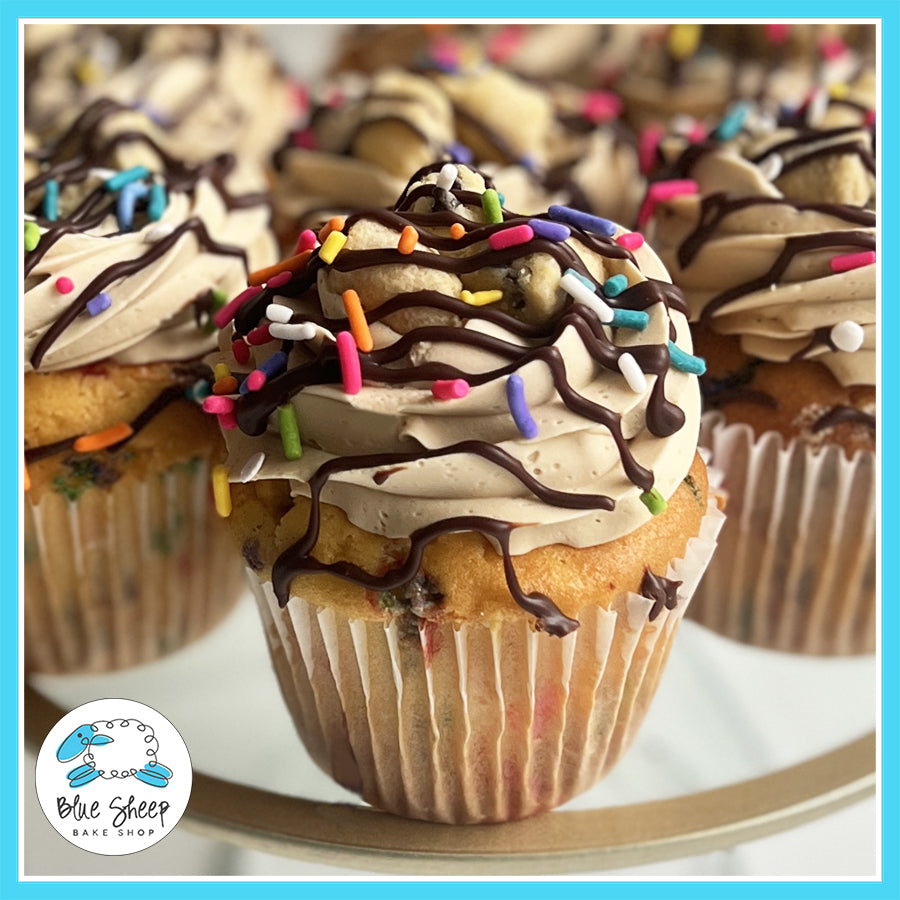 Funfetti cupcakes with cookie dough filling, topped with cookie dough buttercream, ganache drizzle, sprinkles, and cookie dough bites.