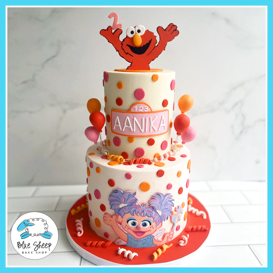 Two-tier Elmo and Abby Cadabby themed birthday cake with polka dots, balloons, and personalized name plaque.