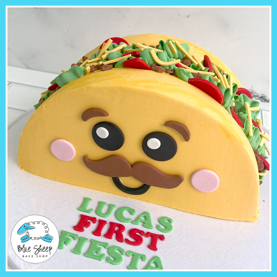 taco-shaped cake with happy face and fondant decorations for a first birthday fiesta.