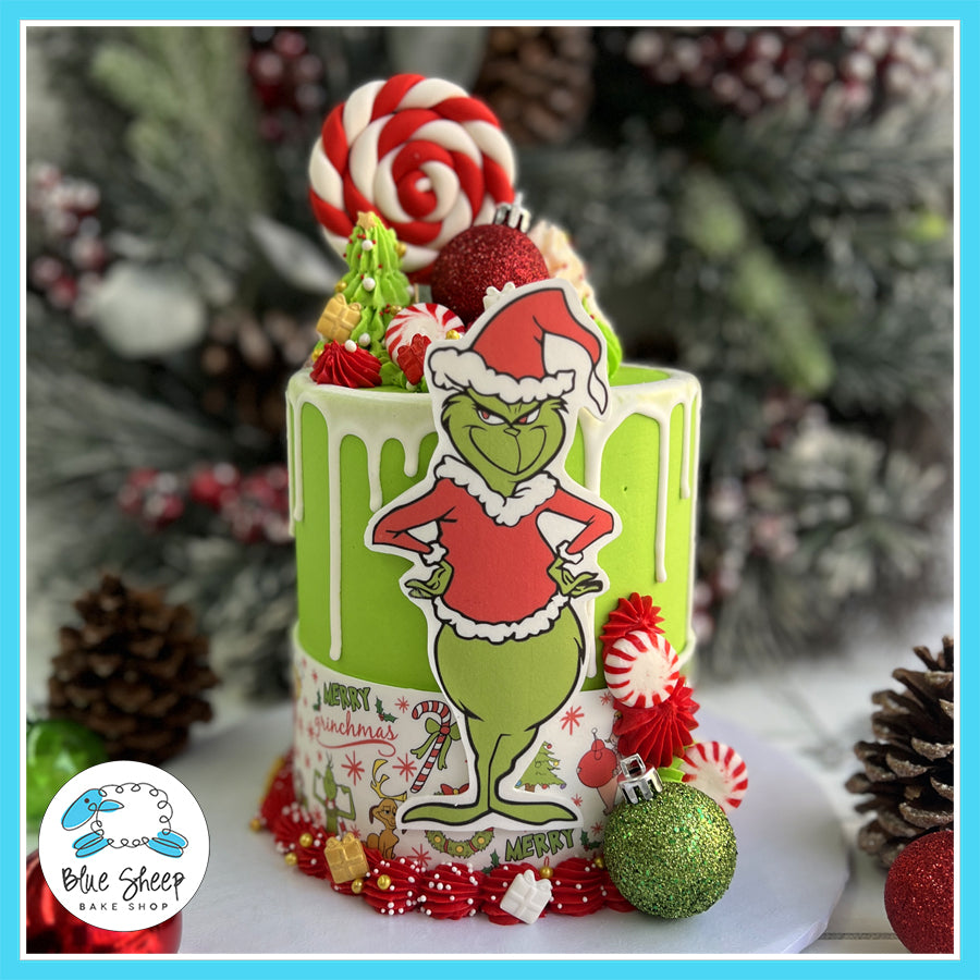 Grinch Christmas Cake with green frosting, white chocolate drip, festive Grinch topper, ornaments, and holiday decorations.