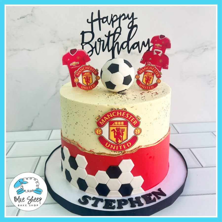 Custom Manchester United soccer birthday cake with edible jerseys, soccer ball toppers, and hexagonal fondant design in red, white, and black. Perfect for soccer fans.