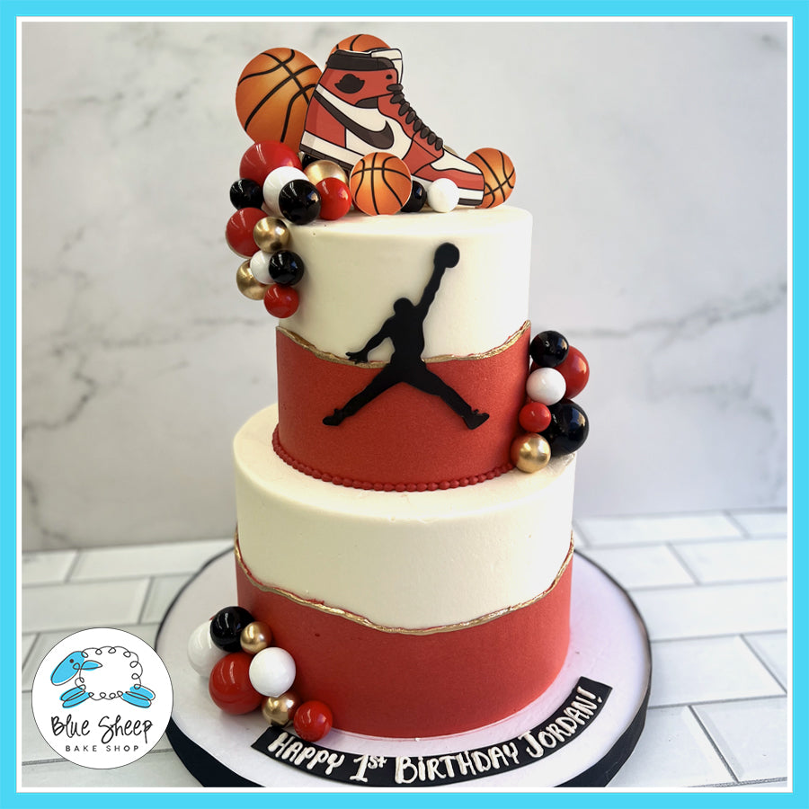 Michael Jordan basketball-themed 1st birthday cake with a red and white design, Air Jordan sneaker, and Jumpman silhouette by Blue Sheep Bake Shop in Somerville, NJ.