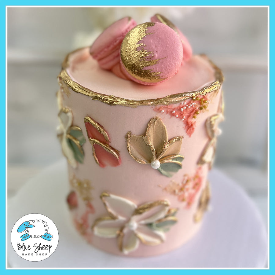 Pink floral cake with gold accents, 3D flower decorations, and gold-brushed macarons by Blue Sheep Bake Shop.