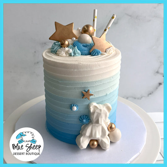 Moon and Stars Teddy custom cake with gradient blue and white design, gold stars, clouds, and a teddy bear figure.