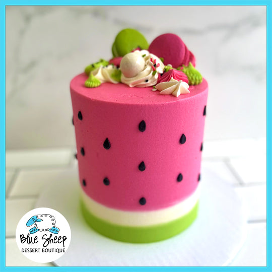 Watermelon themed custom birthday cake with pink and green design, black seeds, and macaron decorations.