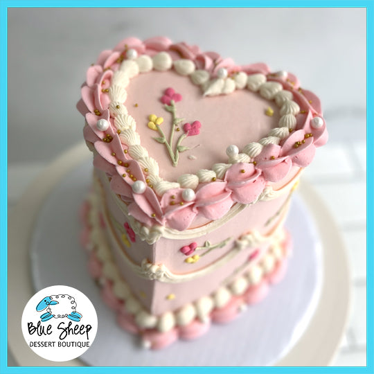 Wildflower heart-shaped custom birthday cake with pink frosting and delicate floral decorations.