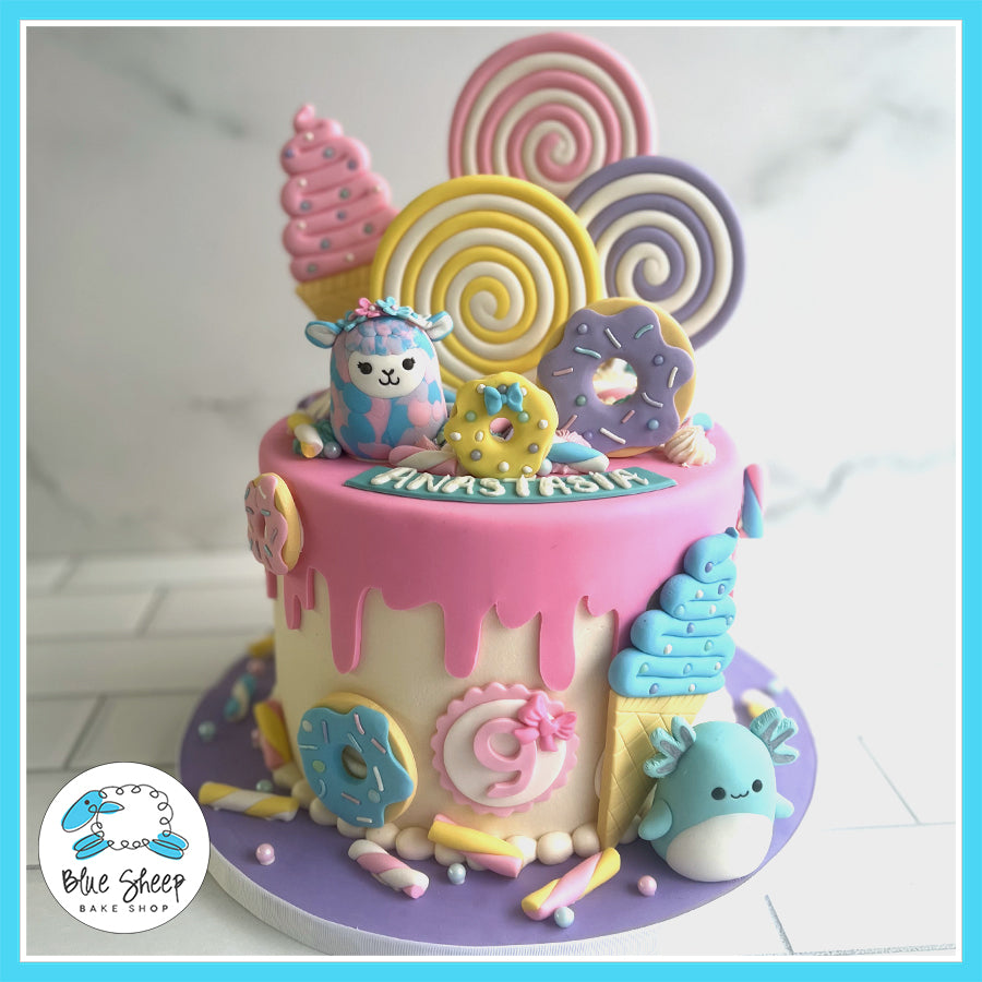 Pastel candy-themed birthday cake with fondant donuts, lollipops, ice cream, and cute animal figurines by Blue Sheep Bake Shop in Somerville, NJ.