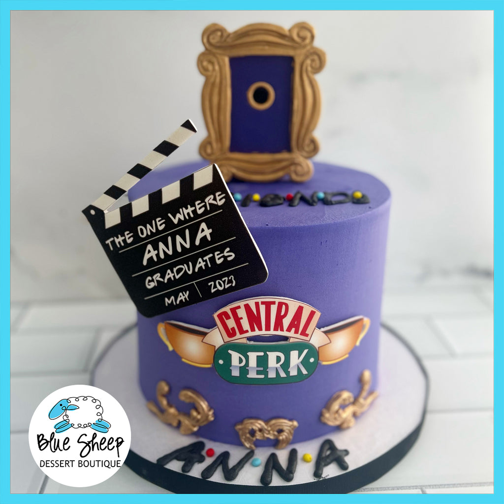 Custom Friends-themed birthday cake with iconic Central Perk logo, director's clapboard, and colorful decorations on a purple buttercream backdrop.