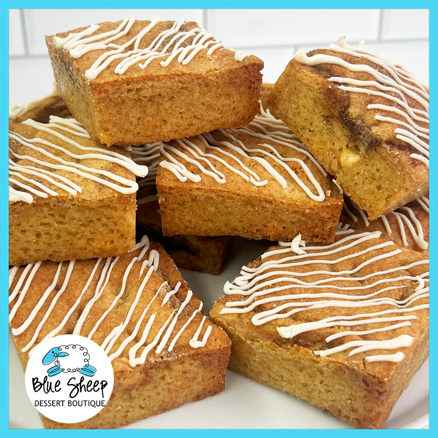 A pile of fresh snickerdoodle blondies with white chocolate drizzle from Blue Sheep Dessert Boutique.