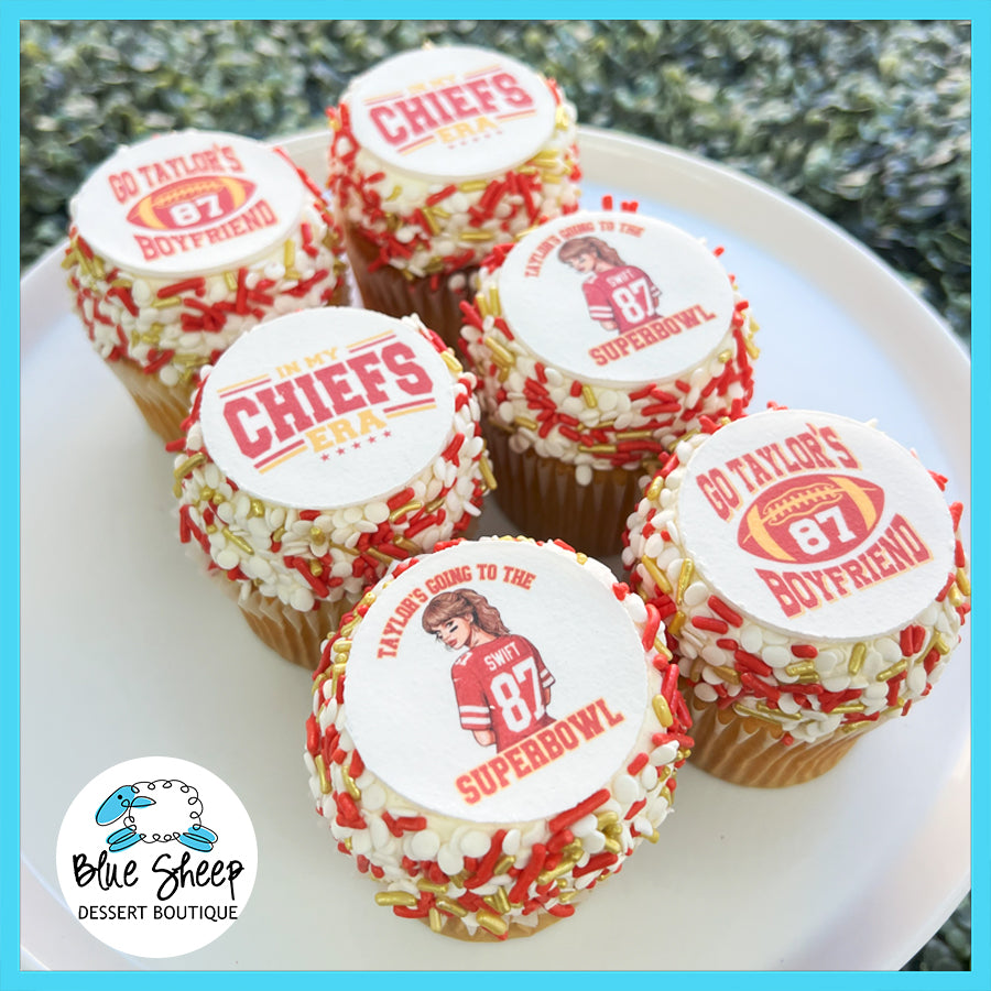 Assortment of Super Bowl-themed cupcakes with a Taylor Swift twist, featuring red and gold sprinkles, Chiefs-inspired decorations, and toppers with Taylor Swift references.
