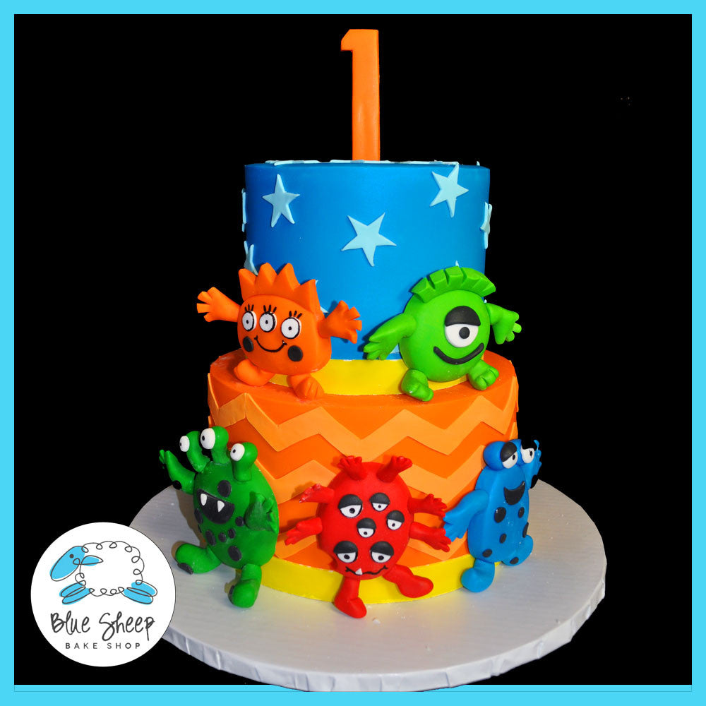 blue, red, and orange 1st birthday cake featuring funny monsters