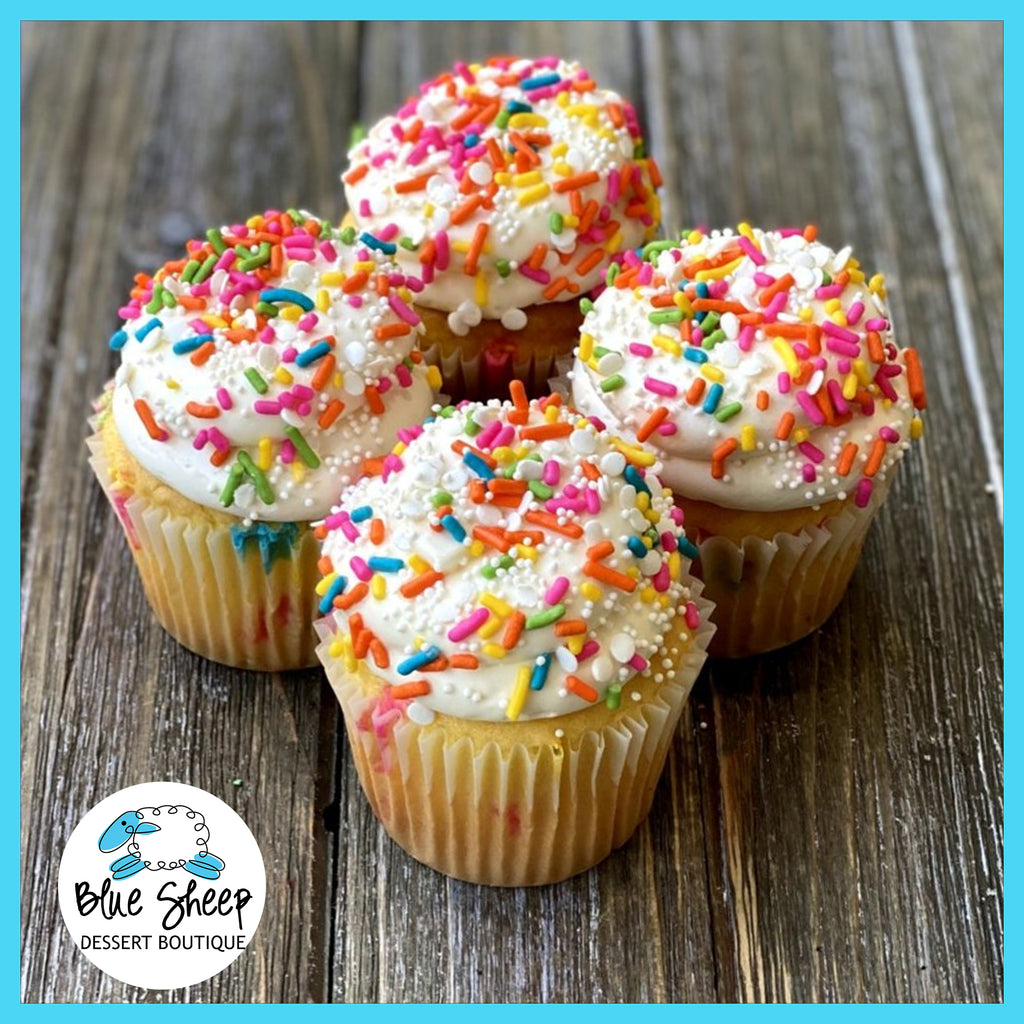 Vanilla birthday cupcakes topped with swirls of white Swiss buttercream and colorful sprinkles 