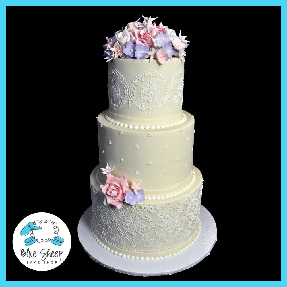 three tiered wedding cake with sugar flowers and lace